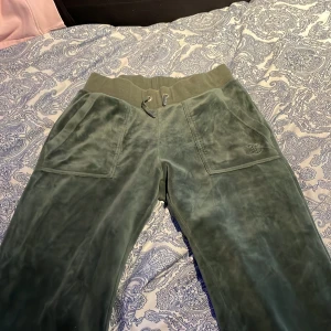 Gröna mjukisbyxor från Juicy Couture - Snygga gröna mjukisbyxor från Juicy Couture i storlek XS. Byxorna har en bekväm resårmidja med snörning och praktiska fickor både fram och bak. Perfekta för en avslappnad stil.