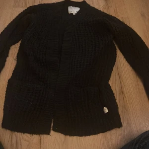 Svart stickad kofta från 157 - Mysig svart stickad kofta från 157 med långa ärmar och praktiska fickor framtill. Perfekt för kyliga dagar när du vill hålla dig varm och bekväm. 🖤