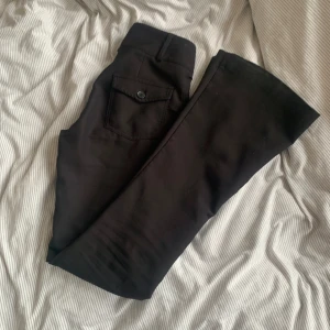 Svarta kostymbyxor från Gina tricot  - Snygga svarta kostymbyxor i storlek 32 från Gina tricot med hög midja och utsvängda ben. Byxorna har två knappar fram och fickor bak. Super fint skick o ny pris 500kr💗
