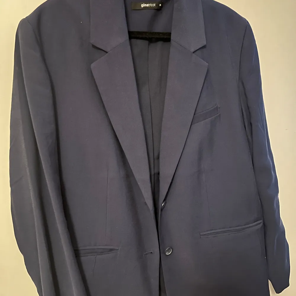 Elegant mörkblå kavaj från Gina Tricot. Kavajen har en enkelknäppt stil och två framfickor. Perfekt för en stilren look. . Puvut & Bleiserit.