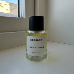 Chocolat Chaud Eau de Parfum från Essnce 50ml - Upptäck doften av Chocolat Chaud från Essnce, en Eau de Parfum med en varm och inbjudande arom. Flaskan är stilren och genomskinlig med en svart kork, vilket ger en elegant touch till din parfymkollektion. 50ml, testad, se bild för mängd.
