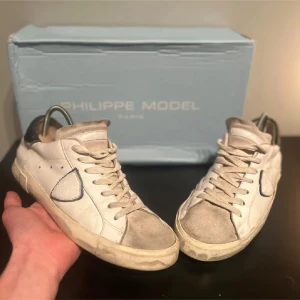 Vita sneakers från Philippe Model - Snygga vita sneakers från Philippe Model med grå detaljer och snörning. Skorna har en klassisk design med en bekväm passform och är perfekta för en stilren look. Skicket är helt okej skriv för fler bilder! Box ingår