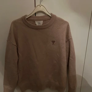Beige tröja från Ami - Säljer en stilren beige tröja från Ami med rund halsringning och ribbade kanter. Perfekt för en avslappnad och trendig look.