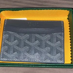 Grå kortfodral - Snyggt grått märkes kortfodral med ikoniska mönster. Perfekt för att hålla dina kort organiserade och stiliga. Kompakt design som passar lätt i fickan.