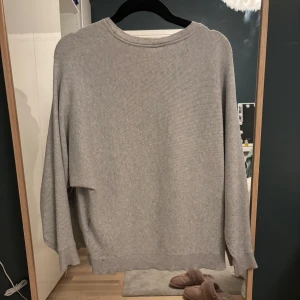Grå stickad tröja - Mysig grå stickad tröja med rund hals och långa ärmar. Perfekt för kyliga dagar och enkel att matcha med olika outfits. Storlek L men krympt så passar S