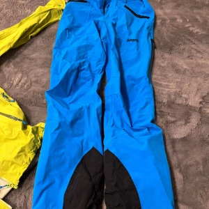 Skidställ  - Säljer nu mitt bergans skidset då det inte kom till mer användning, använt totalt 2 veckor i backen. Jackan och byxorna är i väl skick, jag två små små hål på ryggen av jackan (se bild) och byxorna har lite lätta skador från pjäxorna vid hälen (se bild). Utöver det ett grymt skidset, som är som nytt  Pris: Byxorna storlek S nypris 2699kr: säljer för 1600kr Jackan storlek M nypris 2999kr: säljer för 1800kr Köp båda ihop för 2500kr (nypris ihop 5698kr) Pris kan diskuteras!