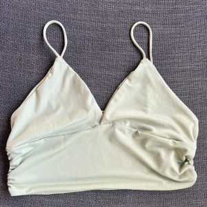 Ljusgrön topp - Säljer en superfin grön (mycket grönare i verkligheten) topp med smala axelband. Toppen har en enkel och stilren design med rynkade detaljer på sidorna som ger en snygg touch. Perfekt för sommardagar eller som ett lager under en kofta. Materialet känns mjukt och skönt mot huden.