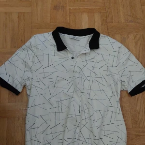 Vit kortärmad t-shirt från LCW Vision - Säljer en vit kortärmad t-shirt från LCW Vision i storlek L. Den har ett coolt mönster med svarta linjer och en svart krage. Perfekt för en avslappnad stil eller en dag ute i solen. Passar bra till jeans eller shorts!