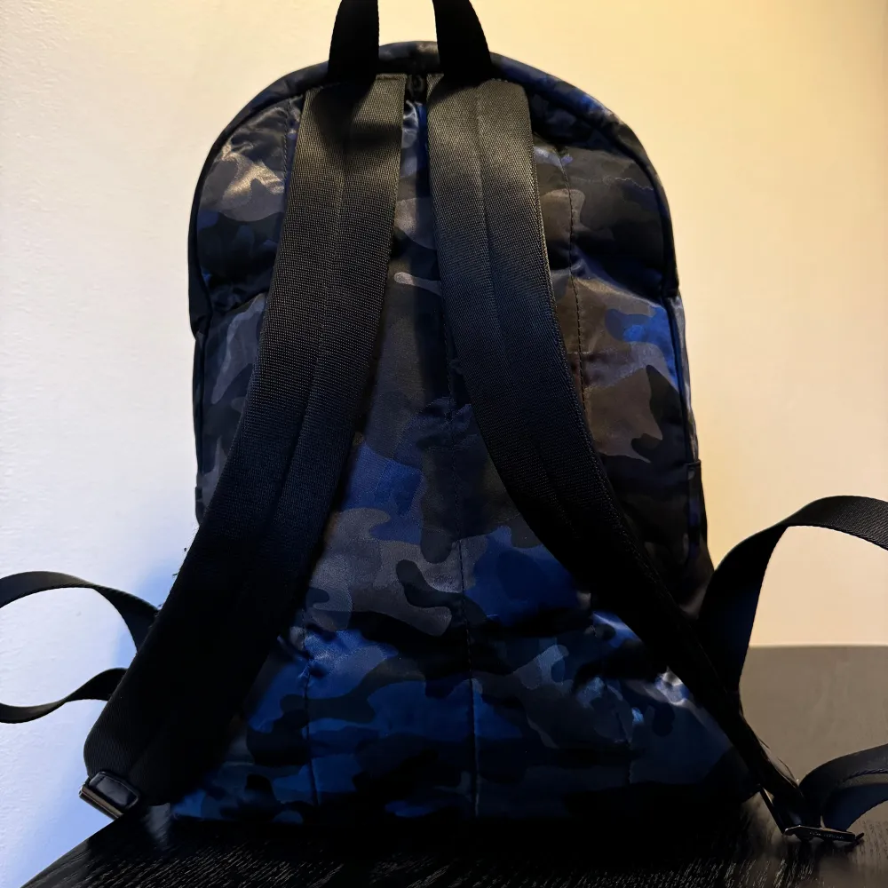 Säljer en snygg ryggsäck från Michael Kors i ett coolt blått och svart camouflage-mönster. Den har en praktisk dragkedja framtill och justerbara axelremmar. Perfekt för vardagsbruk eller skolan. Ryggsäcken är i mycket bra skick och redo för nya äventyr!. Laukut & Käsilaukut.