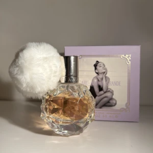 Ariana grande parfym ‘Ari’ - Säljer en superfin parfym från Ariana Grande med en fluffig vit boll på korken som rymmer 50ml Flaskan är kristallformad och innehåller en doft med toppnoter av hallon, päron och grapefrukt, mellannoter av vaniljorkidé, ros och liljekonvalj, samt basnoter av marshmallow, mysk och träiga toner. Perfekt för dig som älskar söta och blommiga dofter! Jämförs pris: 650kr