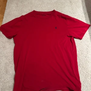Röd t-shirt från Polo Ralph Lauren - Säljer en klassisk röd t-shirt från Polo Ralph Lauren i bomull. Den har en liten broderad logga på bröstet och är kortärmad. Tror den är i storlek S men är osäker då det suddats ut i tvätten