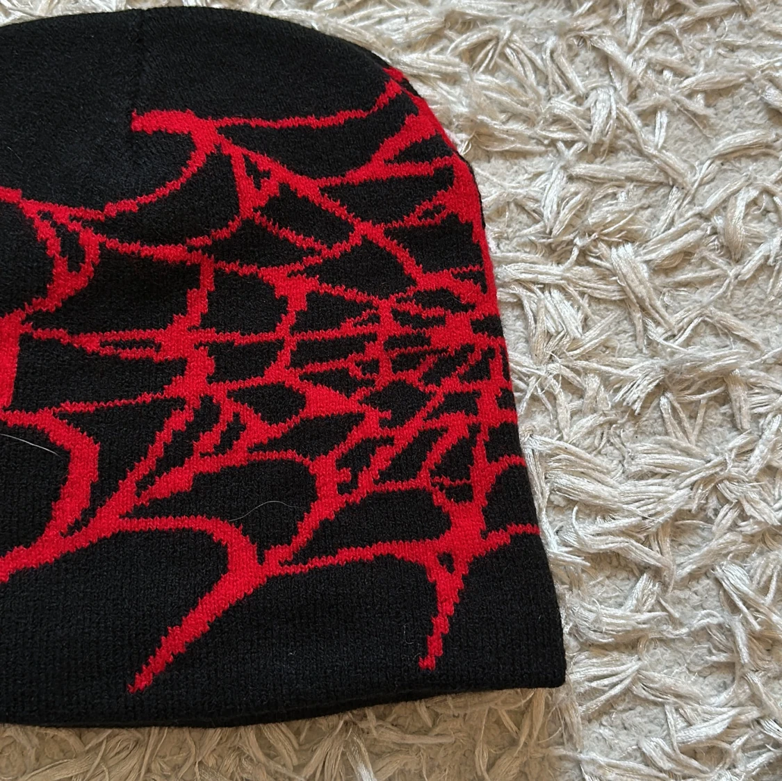 Svart mössa med rött spindelnätsmönster - 91