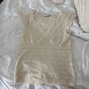 Beige spetsblus från VILA - Säljer en superfin beige spetsblus från VILA i storlek L. Den har en v-ringad design med korta ärmar och ett vackert spetsmönster över hela toppen. Perfekt för både vardag och festliga tillfällen. Blusen är i mycket bra skick och redo för en ny ägare!Den passar om man har s i kläder ❤️