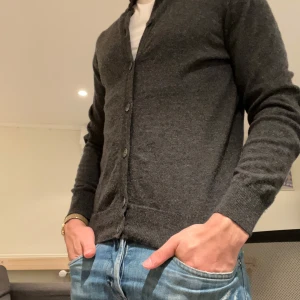 Mörkgrå kofta från Hackett - Säljer en snygg mörkgrå kofta från Hackett, tillverkad i Italien. Den är gjord av en lyxig blandning av merinoull, silke och kashmir. Perfekt för höst och vinter med sina långa ärmar och knappar framtill. Passar både till vardags och lite finare tillfällen.