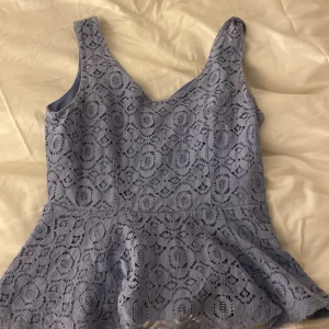 Ljusblå spetslinne från Forever 21 - Säljer ett superfint ljusblått linne från Forever 21 i spets. Det har en dragkedja i ryggen och är ärmlöst med en söt peplumdetalj. Perfekt för sommardagar eller en festlig kväll! 💙