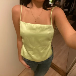 Ljusgrön satinlinne med knyt - Säljer en superfin ljusgrön satinlinne med smala axelband och öppen rygg. Toppen har en snygg knytning bak som ger en extra detalj. Perfekt för sommardagar eller en utekväll! 💚 nästan ny med lappen kvar