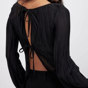 Topp med knyte i ryggen - Superfin topp från NAKD med knyte i ryggen och vida ärmar, går att ha åt båda håll! Nypris 400, i nyskick och endast använd en gång. Skriv för fler bilder!