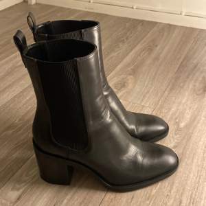 Snygga svarta boots från Zara i skinn med en bekväm klack. De har en stilren design med elastiska paneler på sidorna för enkel på- och avtagning. Perfekta för både vardag och fest!