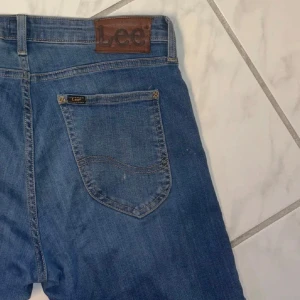 Blå jeans från Lee - Snygga blå jeans från Lee med klassisk femficksdesign och en bekväm passform. De har en medelhög midja och raka ben, vilket ger en tidlös stil. Perfekta för en avslappnad look. Midjemått 74cm, innerbenslängd 68cm.
