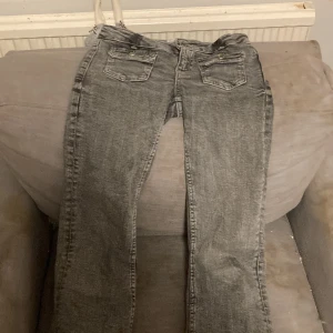 Grå jeans med fickdetaljer - Snygga grå jeans med klassisk femficksdesign och knappar på bakfickorna. Perfekta för en avslappnad stil. De har en rak passform och är tillverkade i ett bekvämt material.