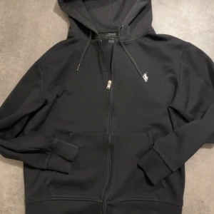 Svart Polo kofta! - En snygg svart polo kofta! En kofta som passar med varje outfit. Koftan är använd ett par gånger och står ba kvar i mitt rum och tänkte att det är dags att bli av med den! Pris kan diskuteras 