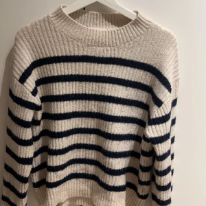 Randig stickad tröja från H&M - Säljer en mysig stickad tröja från H&M i beige med marinblå ränder. Tröjan har en ribbad struktur och långa ärmar. Minns inte vad jag köpte den för då jag köpte den i 2022/2023 men inte använd många gånger alls ❤️