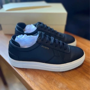 Svarta sneakers från Axel Arigato - Snygga svarta sneakers från Axel Arigato med vit sula. Levereras med originalförpackning och dustbag. Nypris 3000kr. Knappt använda 