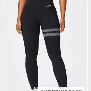 Träningsbyxor Stronger - Snygga svarta leggings från Stronger med ett coolt randigt mönster runt ena benet. Perfekta för träning eller en avslappnad dag. De har en hög midja för extra komfort och stöd. Stl S, använda ett par gånger. Köpte för 700kr om jag inte minns fel🖤