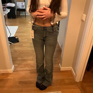 Jeans från Cubus - Snygga högmidjade jeans från Cubus i en klassisk blå denim. De har en bootcut-stil. Jeansen har fickor både fram och bak samt knappar och dragkedja framtill.