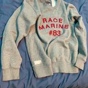 Grå sweatshirt från Race Marine - Säljer en grå sweatshirt från Race Marine .Tröjan har långa ärmar och ribbade muddar vid ärmslut och nederkant. Perfekt för en avslappnad stil. Storlek S