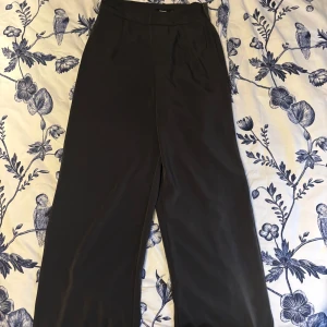 Grå/blå vida byxor från Bik Bok - Snygga grå/blå byxor från Bik Bok med hög midja och vida ben. Perfekta för en stilren look. Tillverkade i ett mjukt och bekvämt material som ger en elegant känsla.