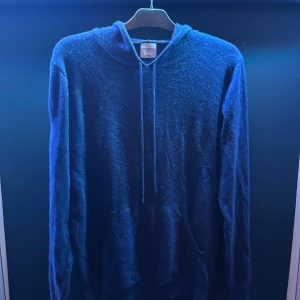  Kashmir tröja  från John Henric  - Säljer en lyxig blå hoodie i mjuk kashmir från John Henric. Tröjan har en klassisk design med huva och dragsko, samt långa ärmar. Perfekt för en stilren och bekväm look. Jätte bra skick det ända är att den är lite knopprig.  Inget medföljs vid köp. Tveka inte på att höra av er vid funderingar🥂