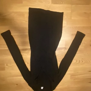 Svart långklänning - Elegant svart långklänning med långärmad design. Klänningen har en ribbad struktur som ger en stilren look. Perfekt för höst och vinter.