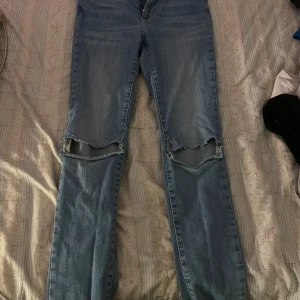 Blå jeans med slitningar - Snygga blå jeans med slitningar över knäna. De har en klassisk femficksdesign och en bekväm passform. Perfekta för en avslappnad stil.