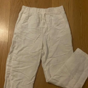 Vita linnebyxor från H&M - Snygga vita linnebyxor från H&M med elastisk midja. Byxorna har en rak passform och är tillverkade i ett linneblandat material. 