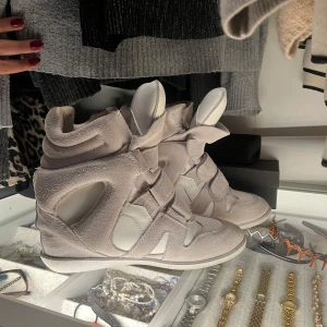 Isabel Marant sneakers i mocka och skinn - Snygga vita sneakers från Isabel Marant i mocka och skinn. De är i superfint skick och mycket varsamt använda!   Detta är en unikare och exklusiv modell med vit sula istället för den klassiska bruna!   Skriv vid frågor! Skulle säga att de är mindre i storleken eftersom att de har en klack, alltså bekvämare att ha större storlek än vanligtvis. Brukar ha 39 1/2 & 40 och dessa har passat mig bra💖Köpta i deras butik i Barcelona för 6900💖
