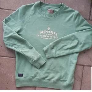 Ljusgrön Morris tröja - Säljer en Snygg ljusgrön sweatshirt från Morris med tryck på bröstet. Tröjan är i bra skick och är perfekt för både höst och vinter. Priset är inte i hugget, skriv ifall du är intresserad eller har några frågor!