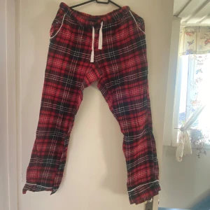 Röd- och svartrutiga mjukisbyxor från bpc - Säljer ett par bekväma mjukisbyxor från bpc i röd- och svartrutigt mönster. Byxorna har en elastisk midja med vit snörning och är perfekta för en avslappnad stil. De har en klassisk passform och är gjorda i mjukt material. Är 170 ich och dom är för korta i benen😢