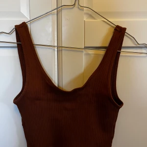 Brun ribbad linnetopp - Snygg brun ribbad linnetopp med breda axelband. Perfekt för en stilren och bekväm look. Passar bra till både jeans och kjol.