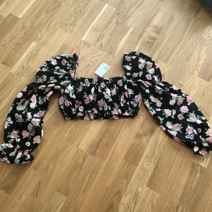 Blommig offshoulder topp - Snygg blommig offshoulder topp med puffiga ärmar. Den har ett elastiskt band vid axlarna och ärmarna för en bekväm passform. Perfekt för en somrig look!