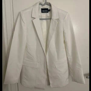 Vit kavaj från Pieces - Snygg vit kavaj från Pieces med klassisk design, är i storlek S. Den här använts 1 gång, inga tecken på användning.