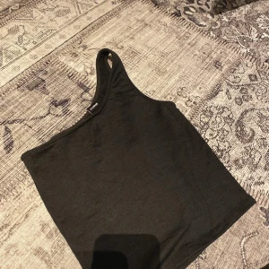 Svart linne från Gina Tricot - Säljer ett stilrent svart linne från Gina Tricot i storlek XS. Linnet har en enkel design med en tight passform och ärmlös stil. Perfekt för lager-på-lager eller som det är.