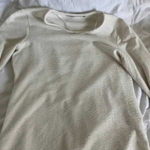 Vit långärmad tröja från Amalia - Säljer en stilren vit tröja från Amalia i storlek M. Tröjan har en texturerad yta och långa ärmar, perfekt för en elegant look. Passar bra till både jeans och kjol.