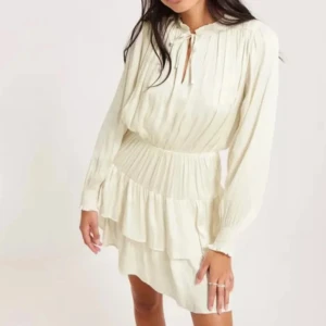 Neo noir  klänning med volanger  - Säljer en söt vit klänning med volanger och långärmade ärmar. Klänningen har en knytning vid halsen och en elastisk midja som ger en fin passform. Perfekt för en somrig look! Inköps pris 1000 kr. Klänningen är i silkes tyg. Klänningen är ifrån neo noir🙌 