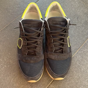 Svart gula Phillipe model  - Snygga svarta phillipe model med gul detalj på hällen. Riktigt bra skick och riktigt sköna att ha på sig. Perfekt sko till våren.                                            