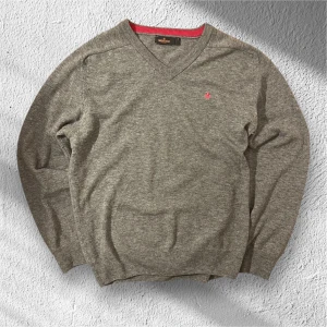 Morris Sweater - Säljer en superfin v-ringad tröja från Morris Stockholm i 100% lammull (storlek M) 🧥✨ Den mjuka, mellangrå nyansen matchas snyggt med en rosa kontrastkant i halsringningen, och den diskreta broderade loggan på bröstet ger en stilren touch. Perfekt för både vardag och festligare tillfällen – hållbar, tidlös och bekväm! Tröjan är i väldigt fint skick, förutom att den är lite nopprig i armhålan. Mitt pris är 399 men man kan få den för endast 359kr om man är eller blir en följare! Ställ gärna frågor