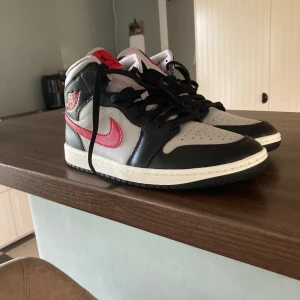 Nike Air Jordans med svart och röd detalj - Snygga Nike Air Jordans med svart och grå bas samt röda detaljer. Skorna har klassisk snörning och en ikonisk design som passar perfekt för sneakerälskare.