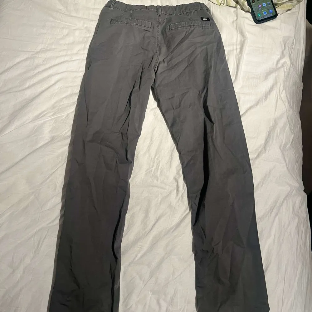 Snygga grå byxor från KappAhl i en klassisk stil. De har en rak passform med knappar och dragkedja framtill. Perfekta för en stilren look.. Farkut & Housut.
