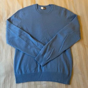Blå kashmirtröja! - Säljer en mjuk och stilren blå kashmirtröja. Tröjan har en klassisk rund hals och långa ärmar med ribbade muddar. Perfekt för en elegant och bekväm look. Passar bra till både jeans och chinos. Det är 100% kashmir! Kom gärna med frågor eller prisförslag!