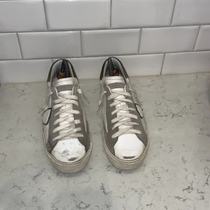 Philippe model - Säljer ett par vita sneakers med gröna detaljer och snörning. Skorna har en klassisk design med en kontrasterande mörkare häl och sula i gummi. Perfekta för en avslappnad stil. Skick 6,5-7 hår av dig vid funderingar. Kan gå ner i pris vid snabb affär